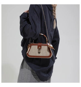 Detail of woven straw crossbody bag with brown leather trim and silk scarf handle