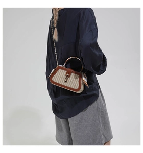 Detail of a woven box bag featuring silk scarf handle and golden chain on a model