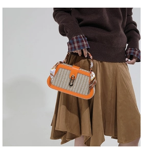 Detail van strooien tas met oranje lederen bies en handvat omwikkeld met een zijden sjaal