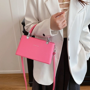 Fashionable pink textured leather crossbody box bag shown on a stylish model in white suit