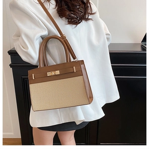 Detail of the brown leather and beige woven fabric panel on a stylish lady's handbag