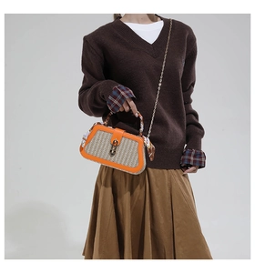 Detail of woven straw bag with orange leather trim and scarf wrapped handle
