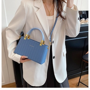 Detail of light blue woven pattern handbag with gold hardware on a stylish model