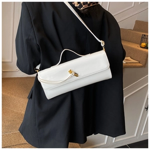 Détail d'un sac baguette en cuir verni blanc avec une boucle métallique dorée en forme de nœud