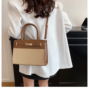 Detailed view of bicolor tote bag with brown leather and woven texture in modern indoor setting