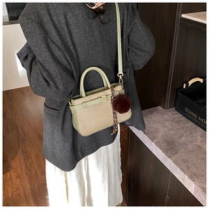 Detail of retro bucket bag with green leather strap and brown faux fur charm
