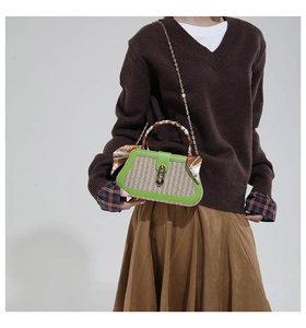 Detail of woven straw box bag with green leather trim, scarf handle and gold chain strap