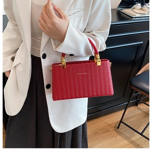 Detail of red box bag with herringbone weave texture and gold metal hardware accents