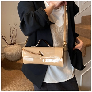 Détail du sac baguette en cuir verni beige avec un élégant fermoir en nœud doré