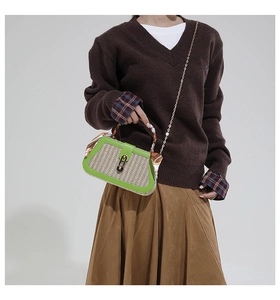 Detail of woven straw box bag with green leather trim and colorful silk scarf handle