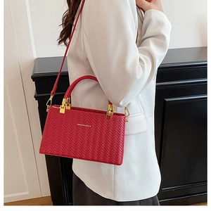 Detail of burgundy woven texture handbag featuring gold hardware and fashion bags logo