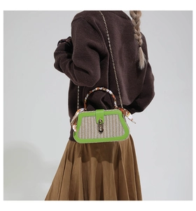 Detail of woven straw box bag with green leather trim and floral silk scarf handle