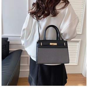 Detail of contrast-color trapezoid handbag featuring woven texture and golden twist lock