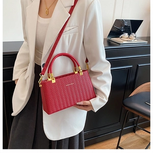 Detail of red woven texture handbag with golden hardware and fashion logo print