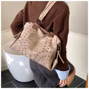 Detail of vintage tote bag featuring retro bronze rivets and soft apricot suede texture