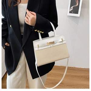 Detail of a contrasting stitched tote bag with gold-tone hardware on a model outfit
