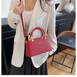 Detail of red crossbody bag with V-shaped woven texture and golden metal hardware