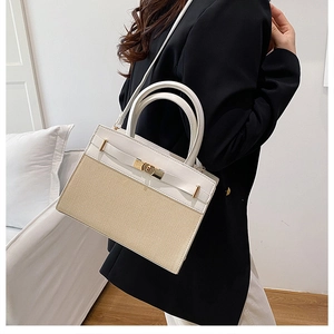 Detail of a white leather and woven straw handbag with a golden twist lock closure