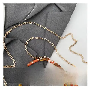 Detail of elegant golden chain strap and colorful silk scarf wrapped around a handbag handle