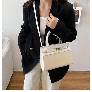 Detail of a two-tone trapezoid handbag with woven texture and white leather accents
