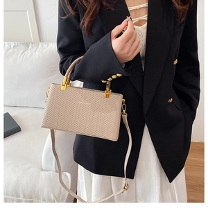 Detail of beige woven texture PU leather crossbody bag with gold handle hardware