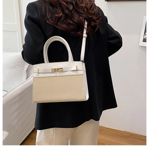 Detail of a color-block patchwork tote bag with gold metal clasp on a female model