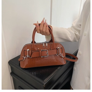 Detail of glossy brown croc-effect handbag featuring a metal buckle and zip closure