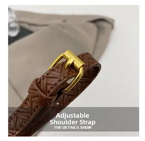 Close-up of adjustable woven leather shoulder strap with gold metal buckle on brown bag