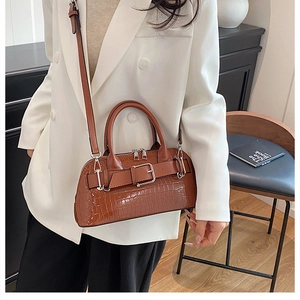 Close-up of brown crocodile texture shell bag with buckle detail and crossbody strap