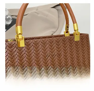 Detail of woven texture handbag with gold metal hardware and brand logo lettering