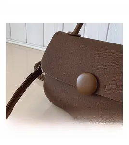 Close-up of brown woven canvas texture and large circular buckle on the handbag