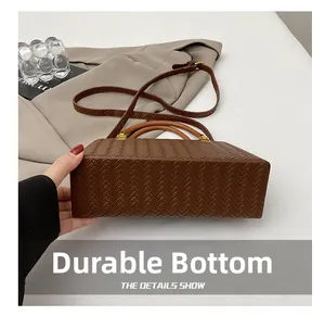 Detail view of woven leather bag bottom featuring wear-resistant material and gold hardware