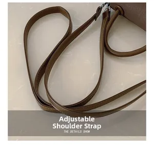 Detailed macro view of the brown leather adjustable shoulder strap with fine stitching