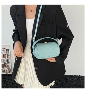 Détail d'un sac à main bleu clair pailleté avec garnitures dorées porté par un mannequin