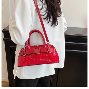 Detail of red crocodile texture shell bag with belt buckle on a white blazer outfit