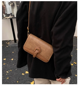Detail of caramel leather and woven patchwork crossbody bag on a black winter coat