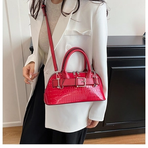 Close-up of red crocodile embossed shell bag with belt buckle detail and silver hardware
