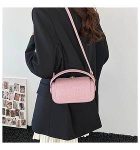 Sac boîte rose pailleté avec détails dorés et bandoulière ajustable porté par mannequin