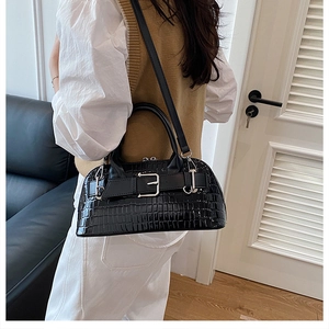 Model wearing black crocodile pattern shell bag with silver buckle and crossbody strap