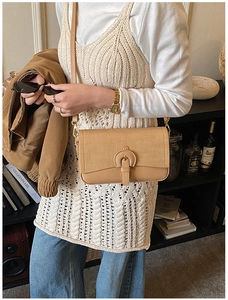 Detail view of a beige woven and leather crossbody bag styled with a summer outfit
