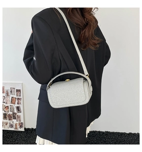 Sac à main argenté à paillettes avec boucle dorée porté avec un blazer noir et jupe