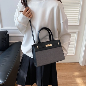 Chic black leather and grey fabric patchwork tote bag with gold buckle on white outfit