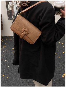 Detail of vintage patchwork shoulder bag with brown textures worn in an autumn street setting