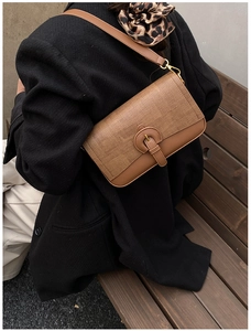 Detail of retro amber brown crossbody bag with mixed textures and gold hardware buckle