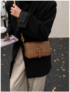 Detail of vintage brown patchwork bag with leather texture and gold hardware on street