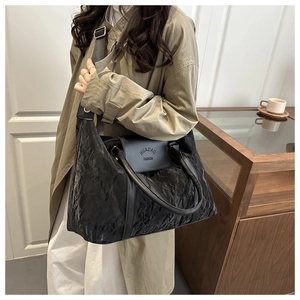 Detail of black pleated tote bag showing HUAJIAO FASHION logo and wide shoulder strap