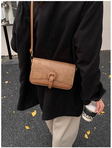 Brown patchwork crossbody bag with textured weave detail worn by model on autumn street