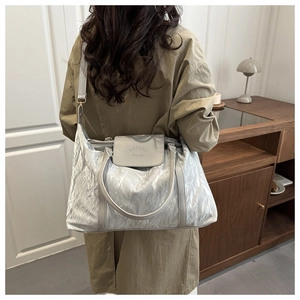 Silver-grey large capacity travel bag with pleated texture shown on a model's shoulder