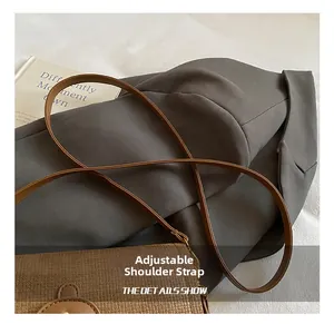 Detail of adjustable shoulder strap on brown woven crossbody bag with metal buckle