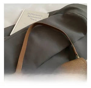 Detail of woven brown shoulder bag showing slim leather strap and gold metal buckles